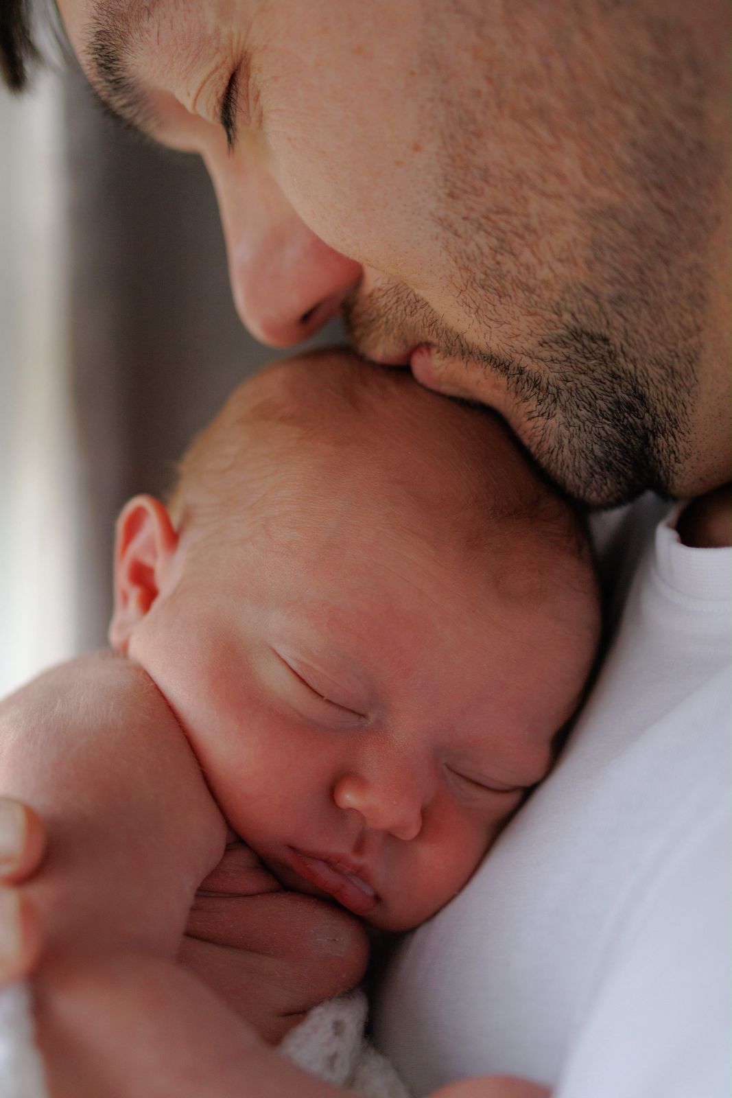 Dad kissing his sleeping newborn on the forehead