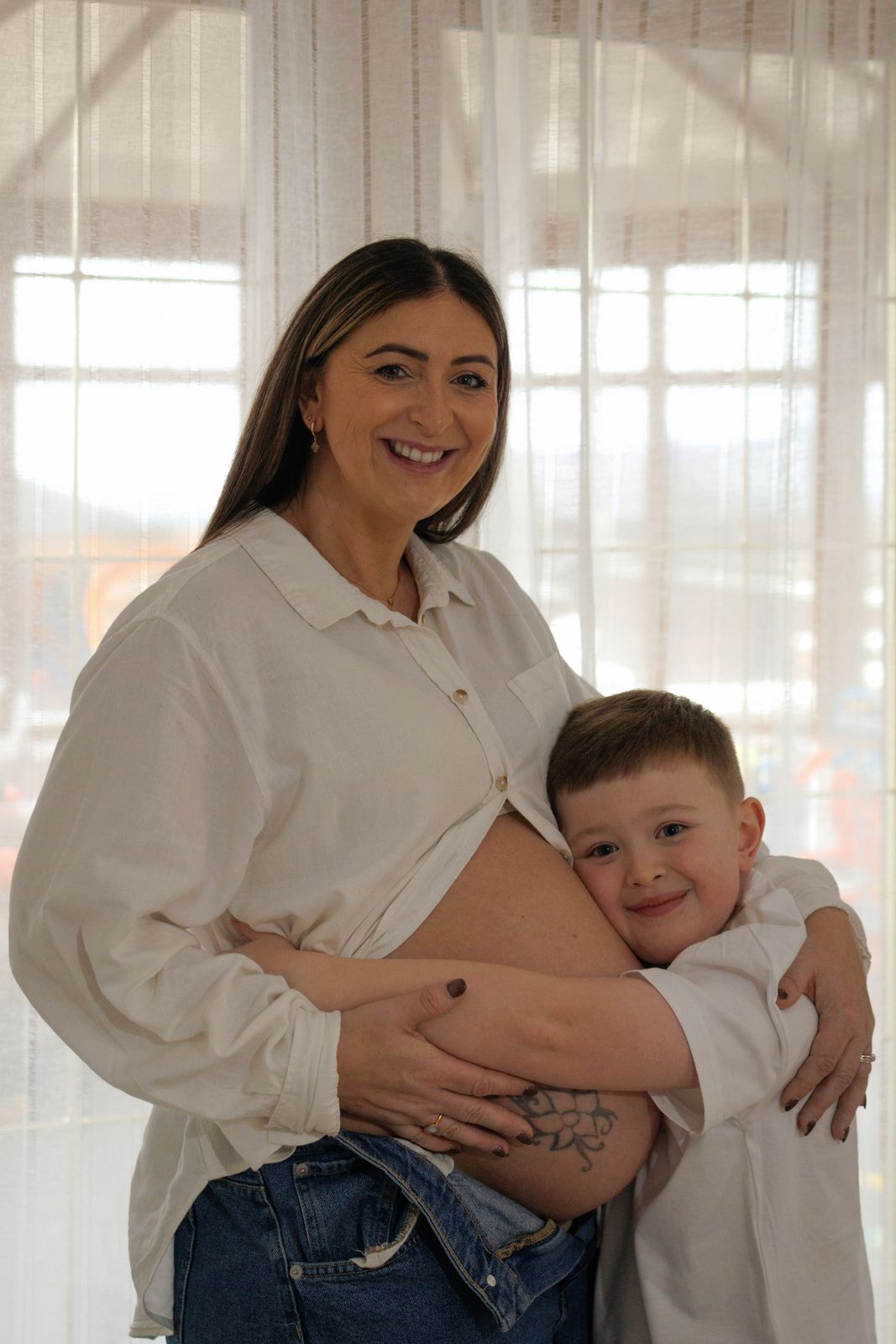Smiling mum-to-be with her son hugging her bump