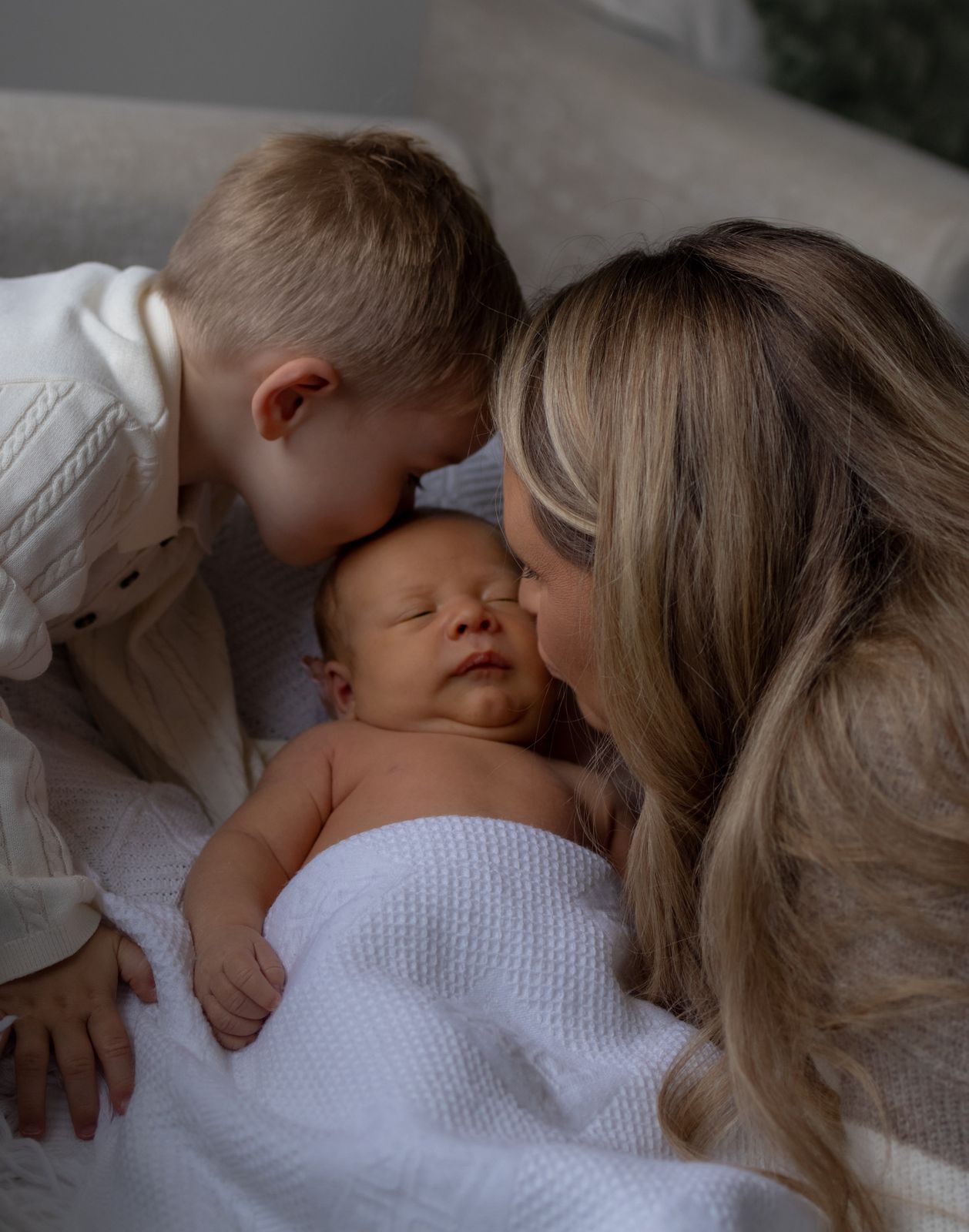 Mum kissing her newborn while big brother looks on