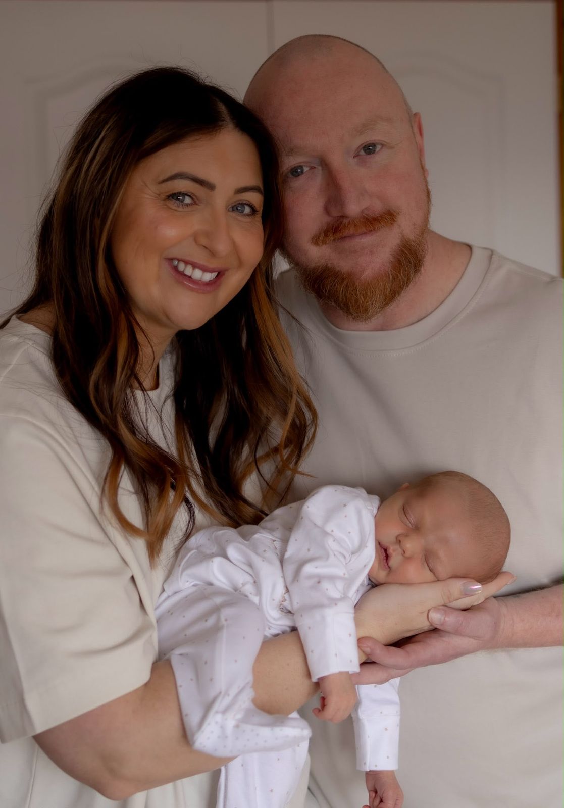 New parents smiling with their sleeping newborn