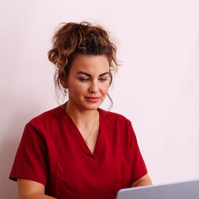 Beauty therapist in red scrubs at her laptop