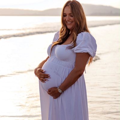 Mum-to-be in a white dress on the beach